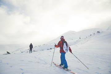 Fototapeta na wymiar Ski touring couple hiking up a summit in the winter mountains