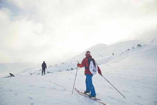 Ski touring couple hiking up a summit in the winter mountains