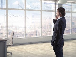 Businessman in modern office talking on phone while anaylzing financial charts on virtual display