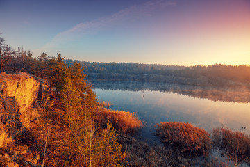 Fototapeta na wymiar Early in the morning, sunrise over a forest lake with steep shores
