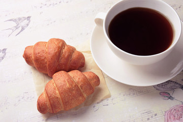 Coffee and pastries: a mug with coffee and a croissant .