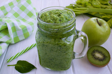 Green smoothies with fruits and vegetables on the white wooden background