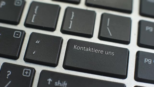 Contact us in German button on computer keyboard, female hand fingers press key