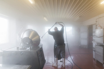 Man using power hose to clean industrial machine