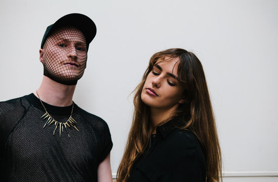 Cool man wearing face mesh and necklace and beautiful young woman
