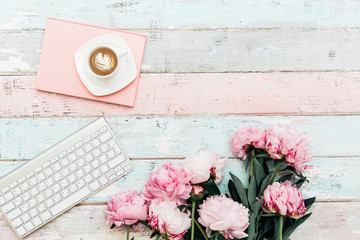 Flat lay home office desk.Pink peony bouquet, coffee and keyboard on wooden background.Top view...