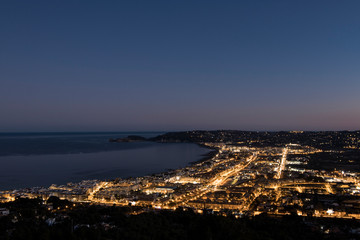 Obraz premium Seaside town just after sunset, city lights lit up