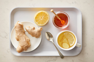 Tray with lemon honey tea with ginger root.