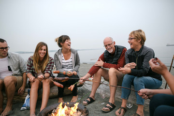 Multi generational family hanging out together aorund fire on th