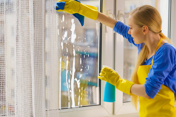 Woman cleaning window at home