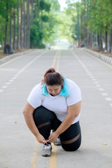 Young fat woman ties her shoelaces on the road