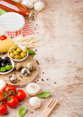 Homemade spaghetti pasta with quail eggs with bottle of tomato sauce and cheese on wooden background. Classic italian village food. Garlic, champignons, black and green olives, oil and spatula.