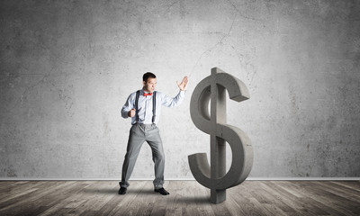 Determined banker man in empty concrete room breaking dollar figure