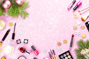 Make up cosmetics, gift box and Christmas decorations on artistic pink background, copy space