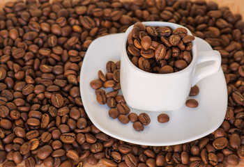Closeup of coffee cup full of roasted coffee beans on the coffee  beans background. selective focus. gold coffee.