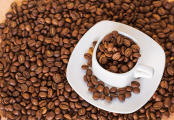 Closeup of coffee cup full of roasted coffee beans on the coffee  beans background. selective focus. gold coffee.