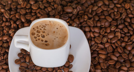  Closeup of white cup with hot coffee with foam on the coffee  beans background. selective focus. gold coffee.