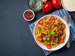 Bolognese pasta. Fusilli with tomato sauce, ground minced beef, basil leaves. Traditional italian cuisine. Top view, copy space.