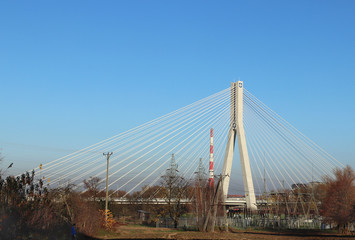Rzeszow, Poland - 9 9 2018: Suspended road bridge across the Wislok River. Metal construction technological structure. Modern architecture. A white cross on a blue background is a symbol of the city.