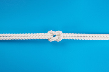 White ship ropes connected by reef knot on blue