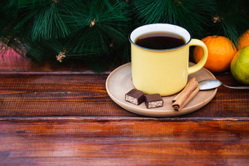  Mug of Hot Tea on a Dark Wooden  Table with Chocolate Candies and Tangerines.