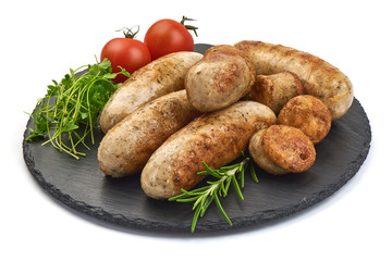 Grilled Bratwurst Sausages with herbs and tomatoes on a shale slate plate, isolated on a white background. Close-up.