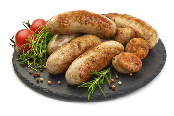 Hot German Bratwurst with herbs and tomatoes on a shale slate plate, isolated on a white background. Close-up