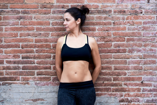 Athletic sportswoman in sportsbra over brick wall.