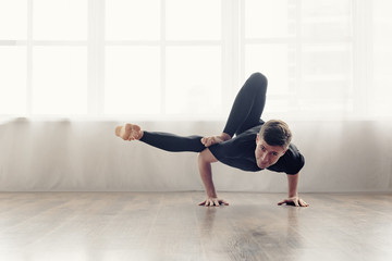 Sporty fit young man doing handstand yoga pose