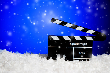 Frozen film clapper / clapperboard blue background with falling snow with copy space