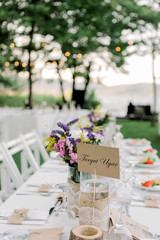 Rows of empty white folding chairs sitting on a lawn. Table setup