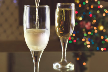 New Year's Eve. Two glasses on the table. Champagne pouring into a glass