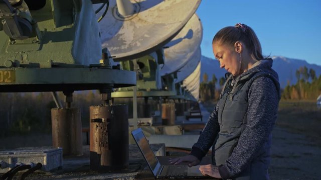 Woman student operator of institute of Solar Terrestrial Physics monitors communication equipment in notebook. Unique array solar radio telescope. Sun Solar Radio Telescope. The 'Quasar' observatory