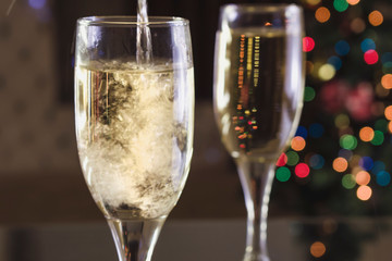 New Year's Eve. Two glasses on the table. Champagne pouring into a glass