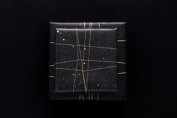 Gifts in black wrapping paper and a golden string on black backg