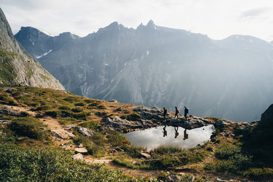 Three hikers walk past lake on top of mountain, Norway