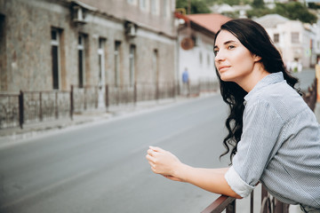 Fototapeta premium beautiful woman standing by rail at the street and looking around. portrait