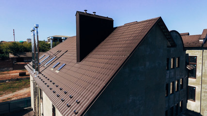 Aerial view of the brown roof of the new original house built on an individual project. New house with an interesting design and modern technology.