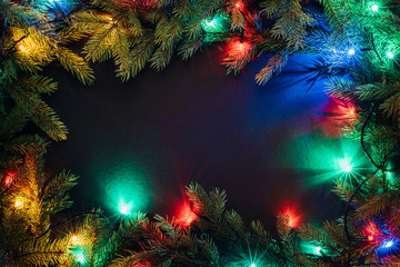Obraz na płótnie Canvas Christmas lights and fir branches on black background