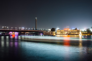 Cairo city center at night, long exposure with light trails of moving boats on the Nile river. © fcerez