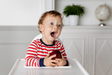 Toddler holding an apple making funny face