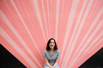 Woman making silly face in front of pink wall