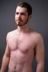 Fototapeta premium Young handsome bearded man shirtless against gray background