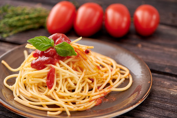 spaghetti with ketchup and Basil on dark wooden background