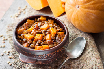 Homemade spicy curry with green lentils, pumpkin and raisins in rustic ceramic bowl