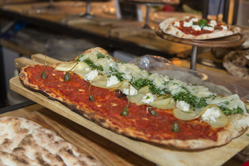 Long Pizza with Basil, Cheese and Capers on a Wooden Baking Sheet..