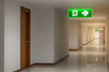 green emergency exit sign in hotel showing the way to escape - obrazy, fototapety, plakaty