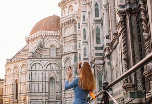 Back view portrait of redhead girl taking picture of Duomo in Florence
