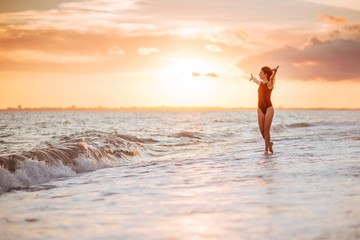 Fototapeta na wymiar carefree woman dancing in the sunset on the beach. vacation vitality healthy living concept