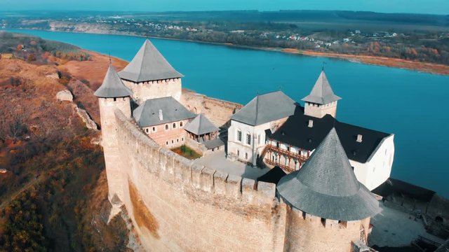 Panorama aerial view of old castle Hotin near river. Khotyn Fortress - medieval castle on yellow autumn hills. Ukraine, Eastern Europe. Architecture of Middle Ages in our time.
